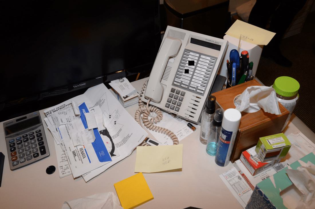 EFTA00001337 - Cluttered office desk with a phone calculator papers and various items