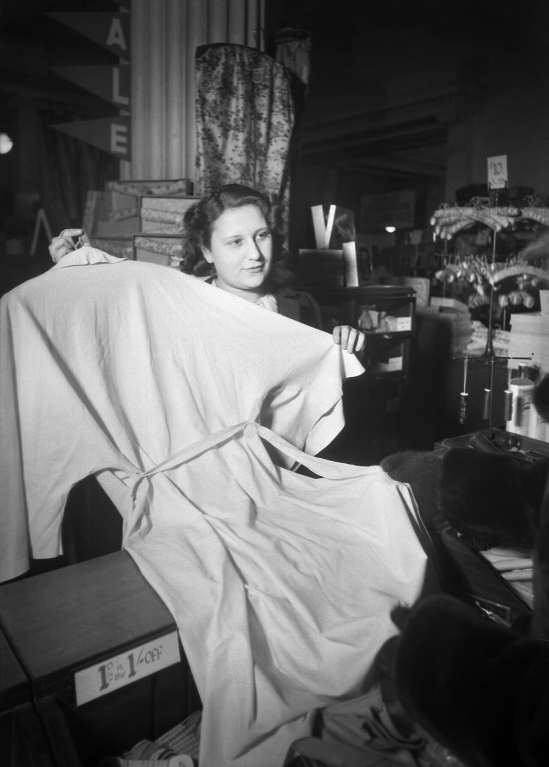 A female shop assistant in Selfridge's displays a white raincoat for use in the blackout, 1940. D75